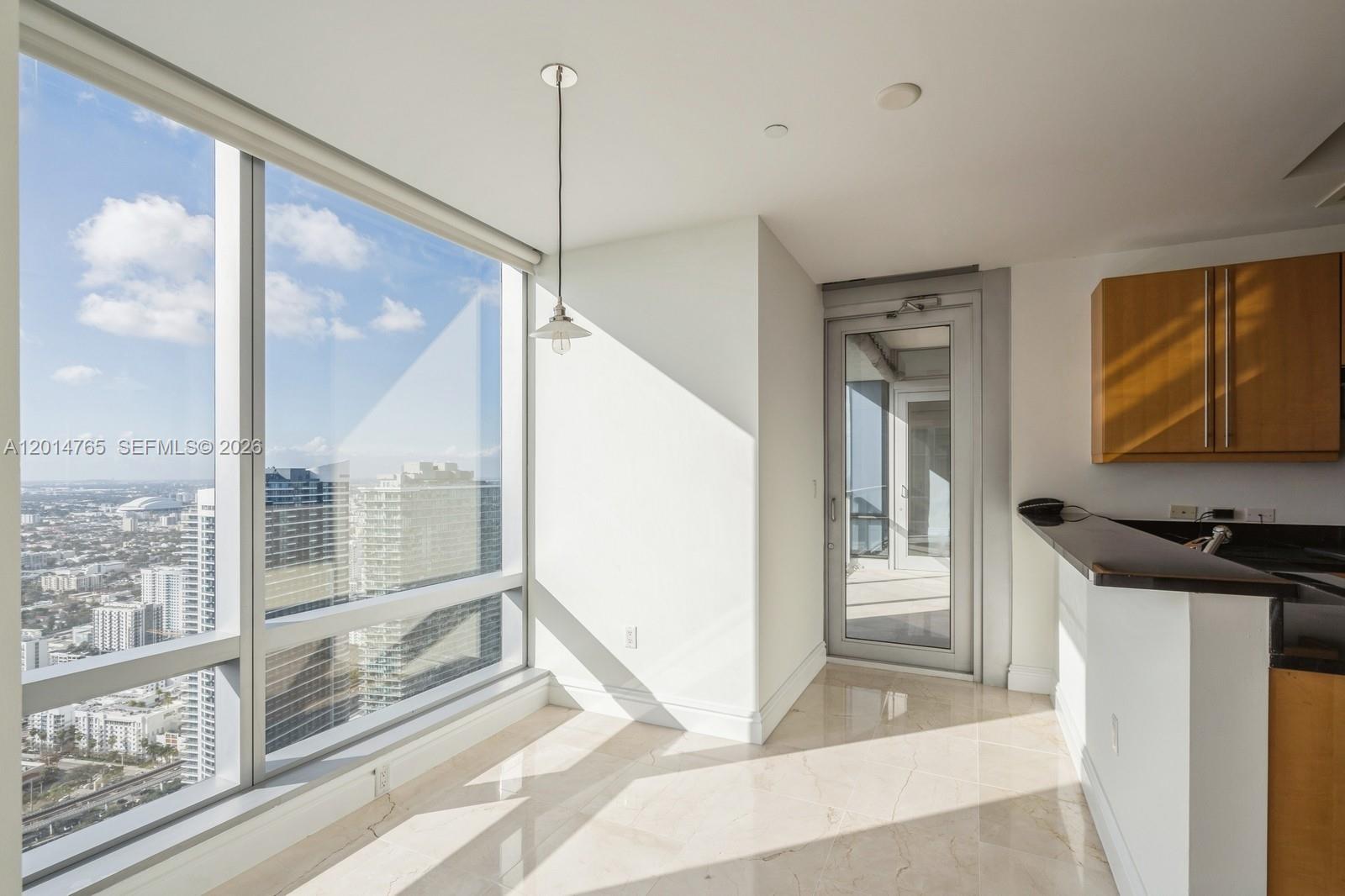 A bright room with floor-to-ceiling windows, tile flooring, a pendant light, and a glass door — 1425 Brickell Ave # 57B, Miami FL 33131, MIAMI, FL