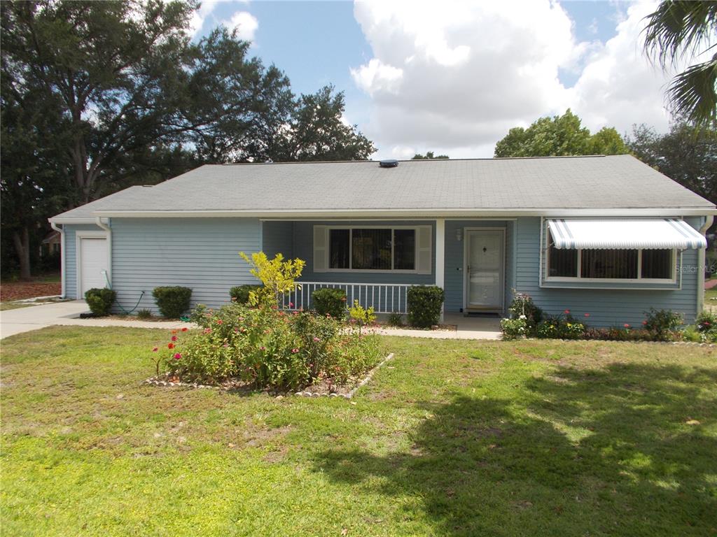 A light blue, single-story house with a gray shingled roof and a front garden — 10877 SW 88TH COURT, OCALA, FL