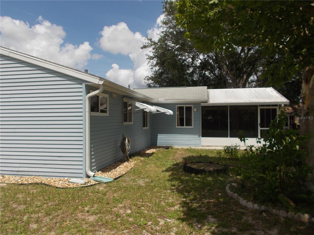 The exterior of a light blue house features a screened-in porch and a gravel border — 10877 SW 88TH COURT, OCALA, FL