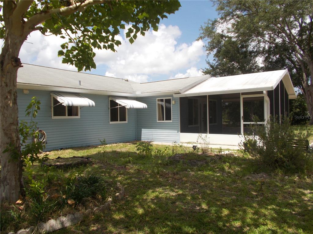 A light blue house with a screened-in porch and two windows with metal awnings — 10877 SW 88TH COURT, OCALA, FL