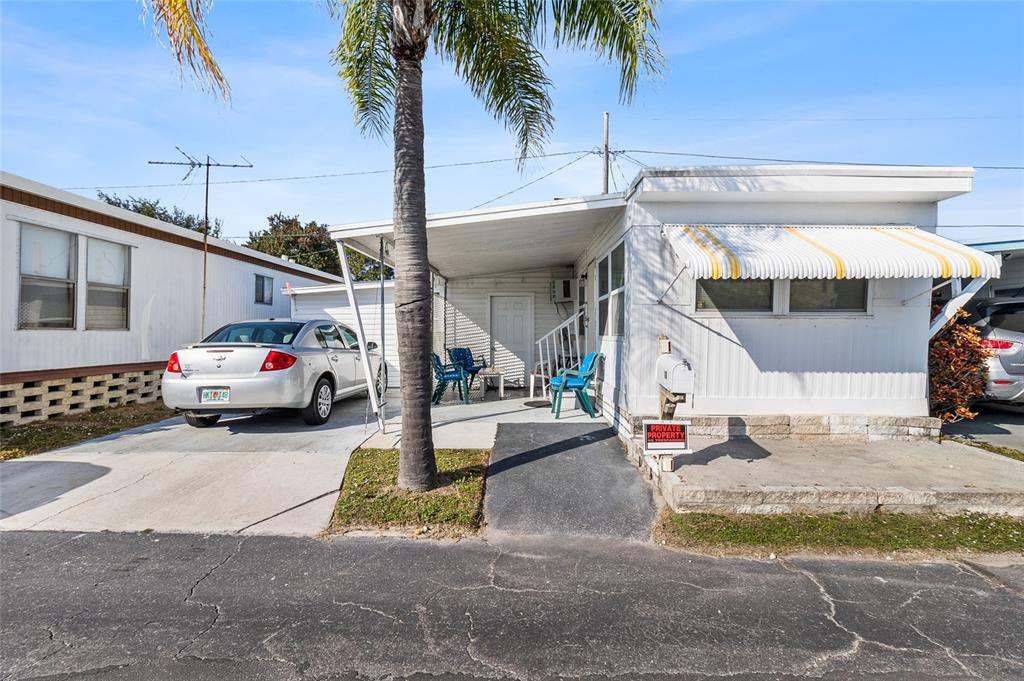 A single-story manufactured home with a carport, a palm tree, and a paved driveway — 12766 SEMINOLE BOULEVARD UNIT 10, LARGO, FL