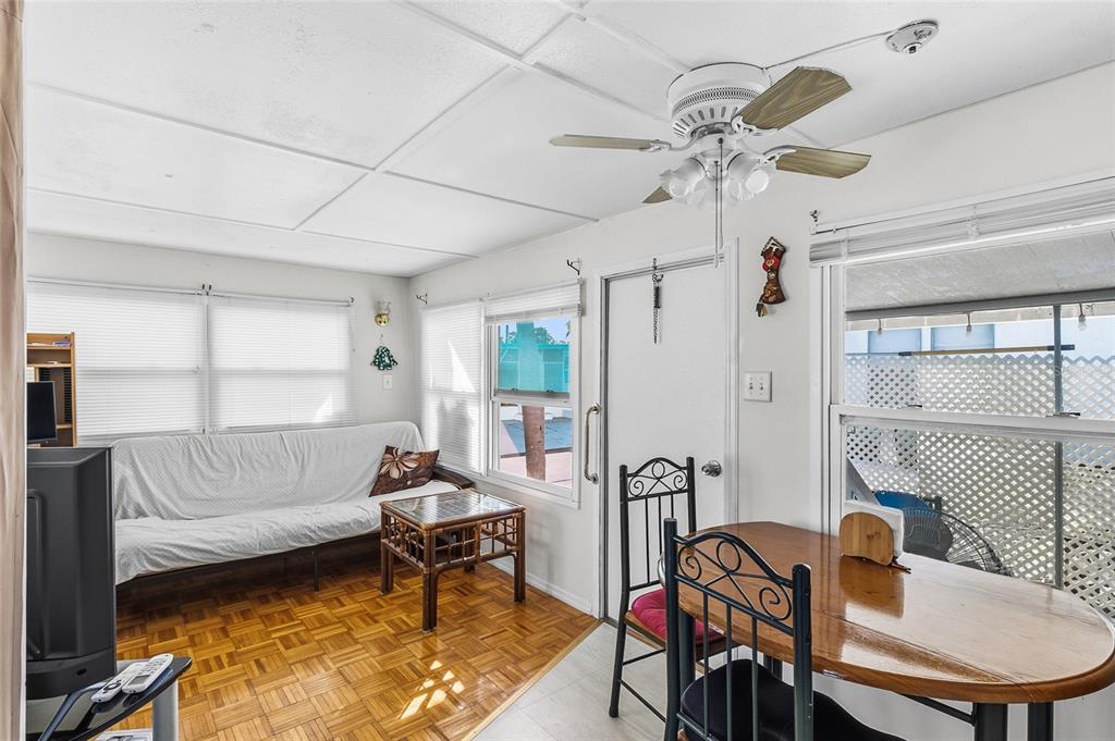 A living and dining area features parquet flooring, a ceiling fan, and a white sofa — 12766 SEMINOLE BOULEVARD UNIT 10, LARGO, FL