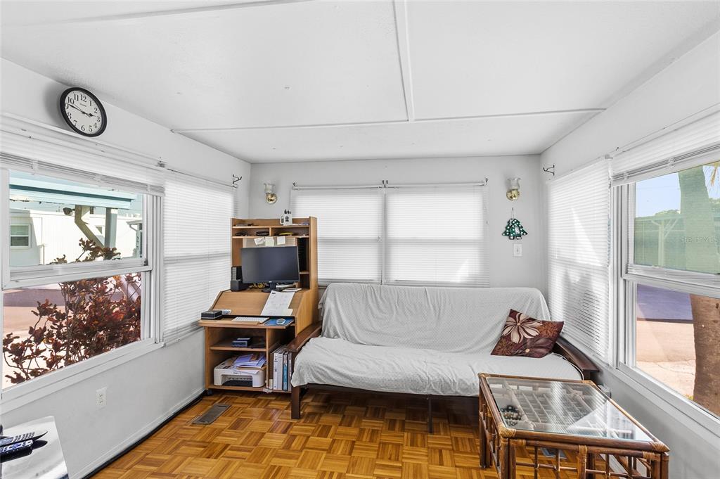 A sunroom features parquet flooring, a futon, a computer desk, and windows on three walls — 12766 SEMINOLE BOULEVARD UNIT 10, LARGO, FL