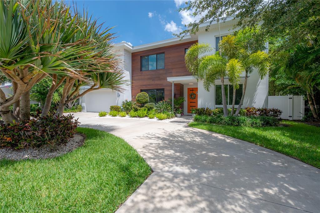A two-story house with a wood-paneled facade, orange front door, and a concrete driveway — 4207 W JETTON AVENUE, TAMPA, FL