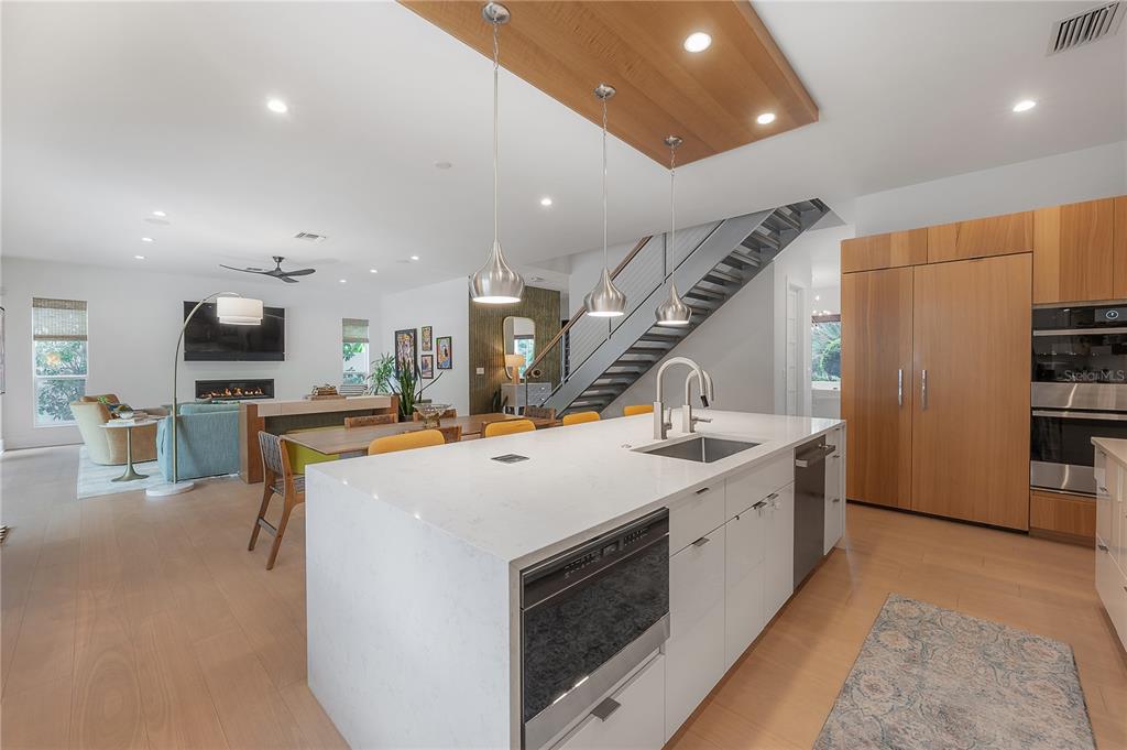 A modern kitchen features white cabinetry, a large quartz island, and a wooden dining table — 4207 W JETTON AVENUE, TAMPA, FL