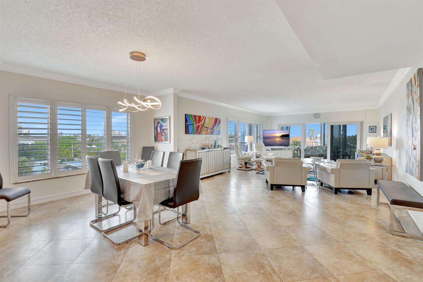 An open-concept living and dining area features tile flooring, modern furniture, and large windows — 220 Macfarlane Drive # 505, Delray Beach FL 33483, DELRAY BEACH, FL