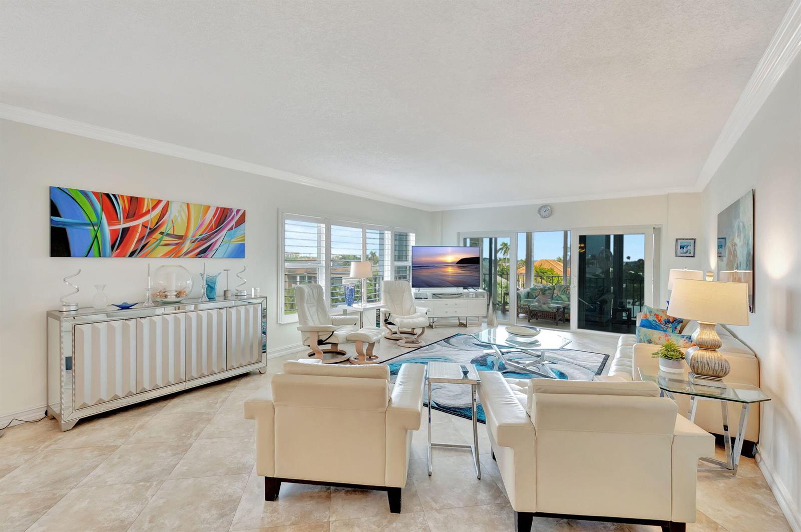 A bright living room features white leather furniture, a mirrored sideboard, and large sliding doors — 220 Macfarlane Drive # 505, Delray Beach FL 33483, DELRAY BEACH, FL