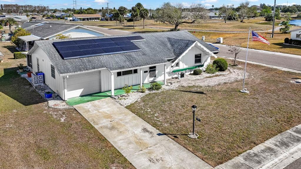 An aerial view of a white single-story house with solar panels and a flag pole — 1001 AUGUSTA DRIVE, SUN CITY CENTER, FL