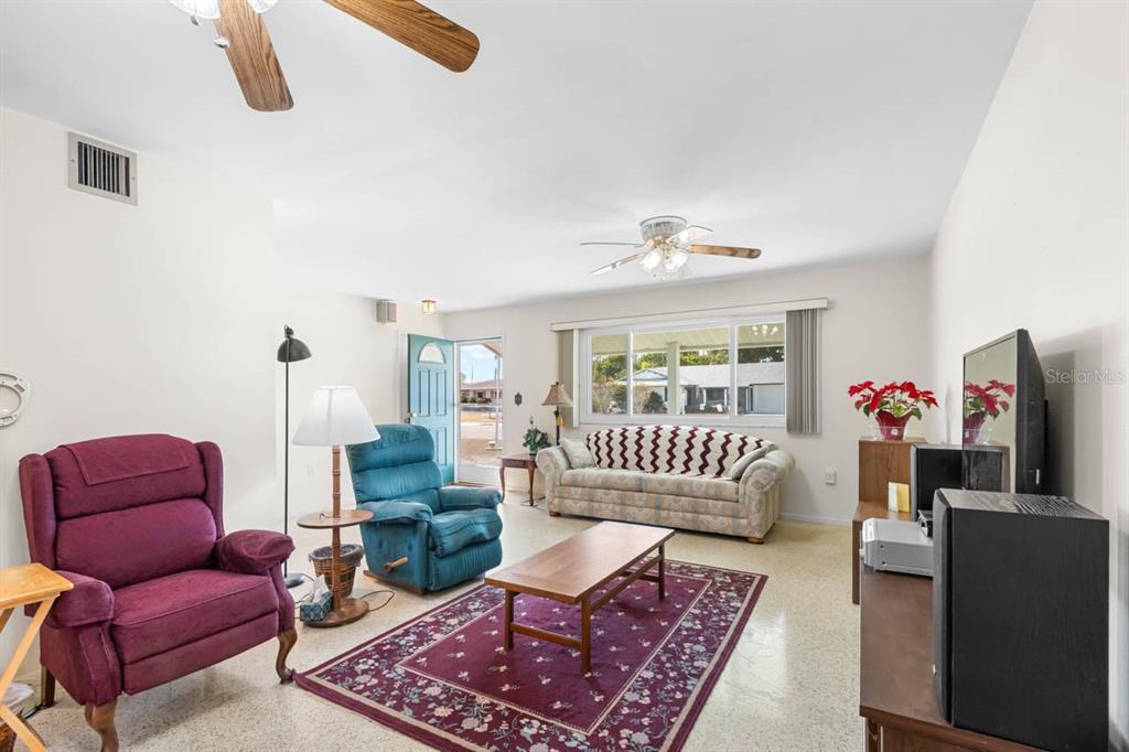 A living room features a purple recliner, a blue recliner, a patterned sofa, and tile flooring — 1001 AUGUSTA DRIVE, SUN CITY CENTER, FL