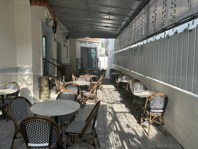 An outdoor patio features multiple small round tables and woven chairs under a metal awning — 929 Collins Ave, Miami Beach FL 33139, MIAMI BEACH, FL