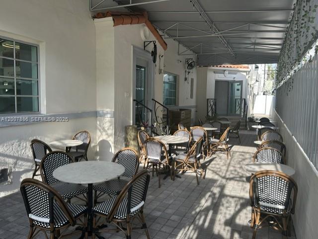 An outdoor patio area features multiple small tables and chairs under a metal awning — 929 Collins Ave, Miami Beach FL 33139, MIAMI BEACH, FL