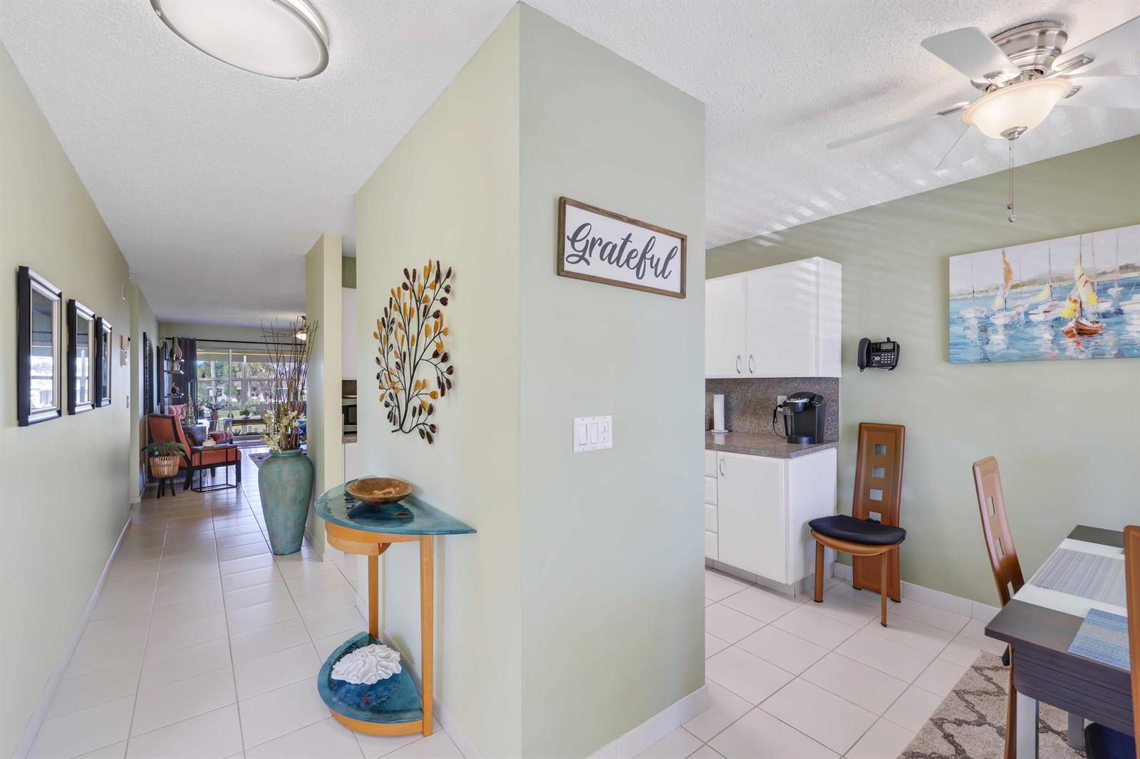 A light-green hallway leads to a dining area with white cabinets and tile flooring — 13757 Flora Place, Delray Beach FL 33484, DELRAY BEACH, FL