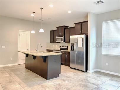 A kitchen features dark wood cabinets, a granite-topped island, and stainless steel appliances — 1445 PETERSON PLACE, SANFORD, FL
