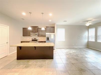 A kitchen with dark cabinets, a granite island, and tile flooring opens to a living area — 1445 PETERSON PLACE, SANFORD, FL