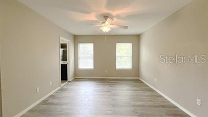 A spacious room with light-colored walls, wood-look flooring, two windows, and a ceiling fan — 1445 PETERSON PLACE, SANFORD, FL