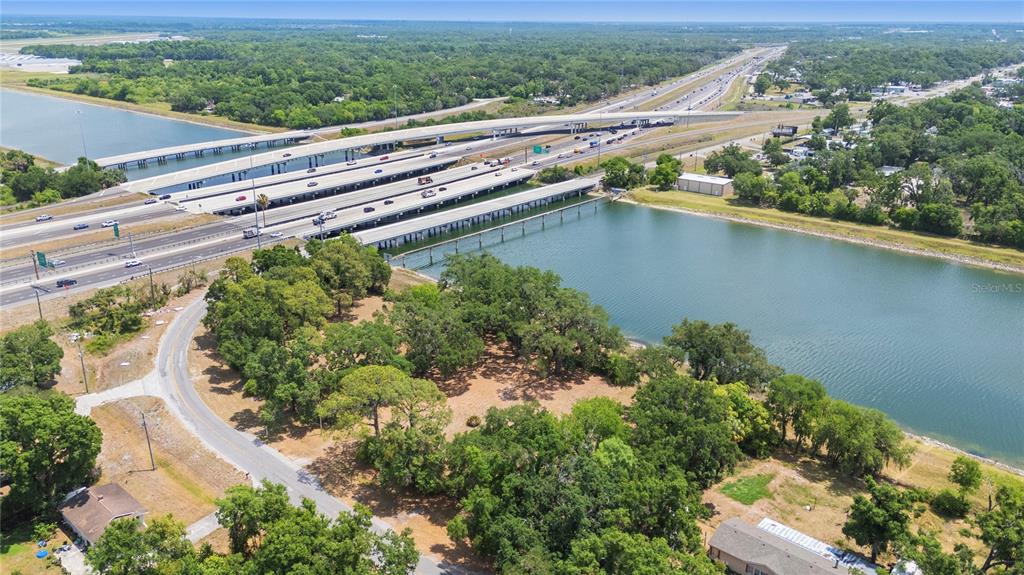 An aerial view shows a highway bridge crossing over a body of water near trees — 5013 GARDEN LANE, TAMPA, FL