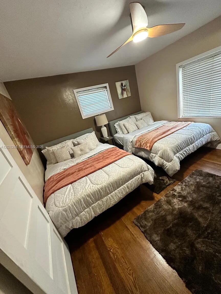 A bedroom features two beds with patterned bedding, wood flooring, and a ceiling fan — 1275 NW 50th St # 0, Miami FL 33142, MIAMI, FL