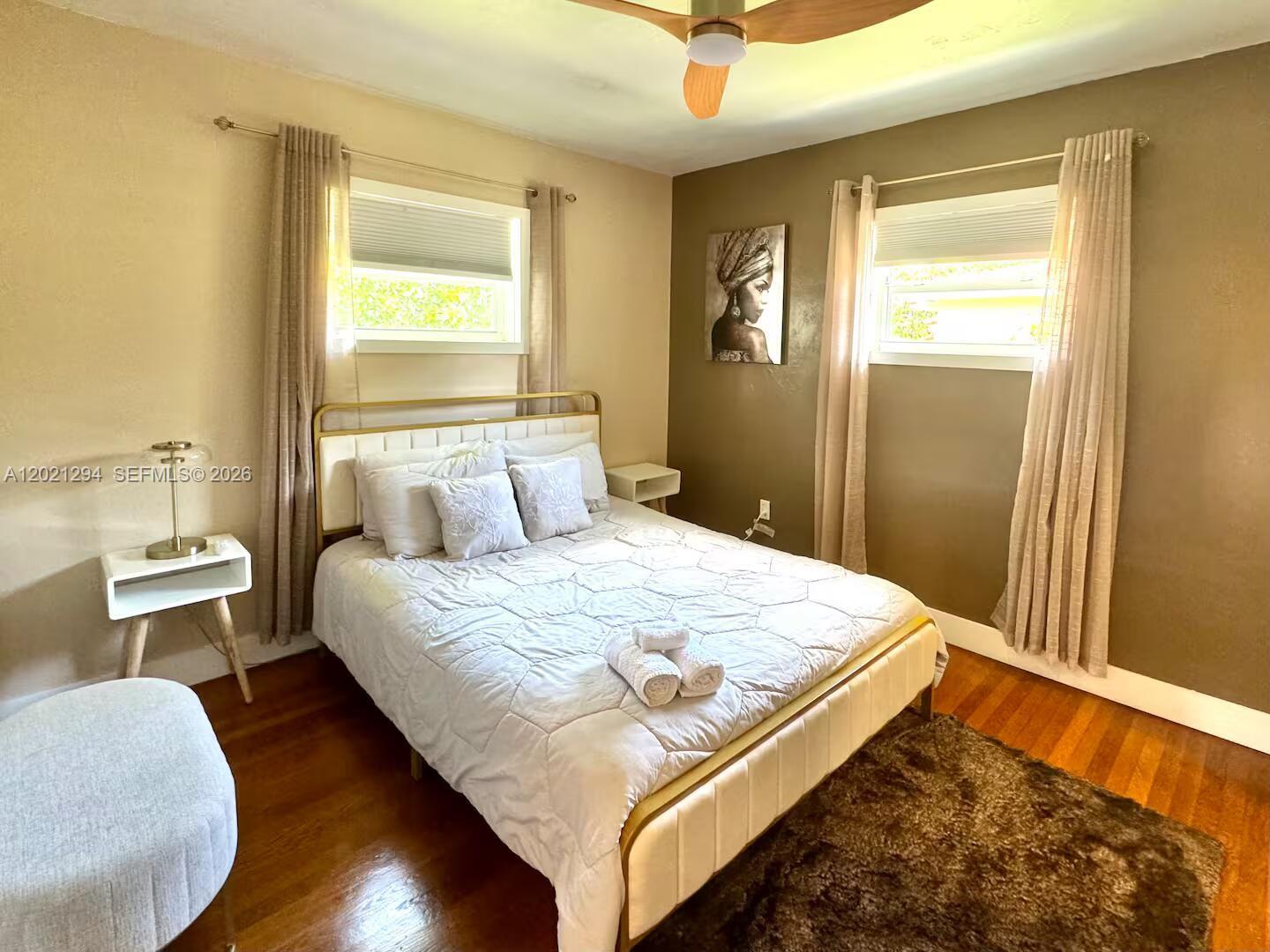 A bedroom features a bed with a gold frame, hardwood floors, and two windows — 1275 NW 50th St # 0, Miami FL 33142, MIAMI, FL