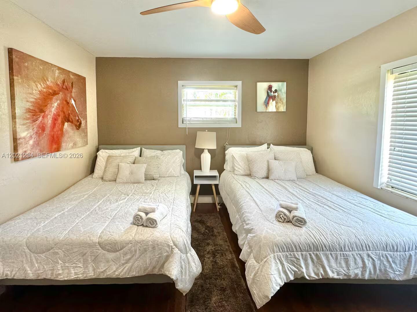 A bedroom features two beds with white bedding, a central nightstand, and wall art — 1275 NW 50th St # 0, Miami FL 33142, MIAMI, FL