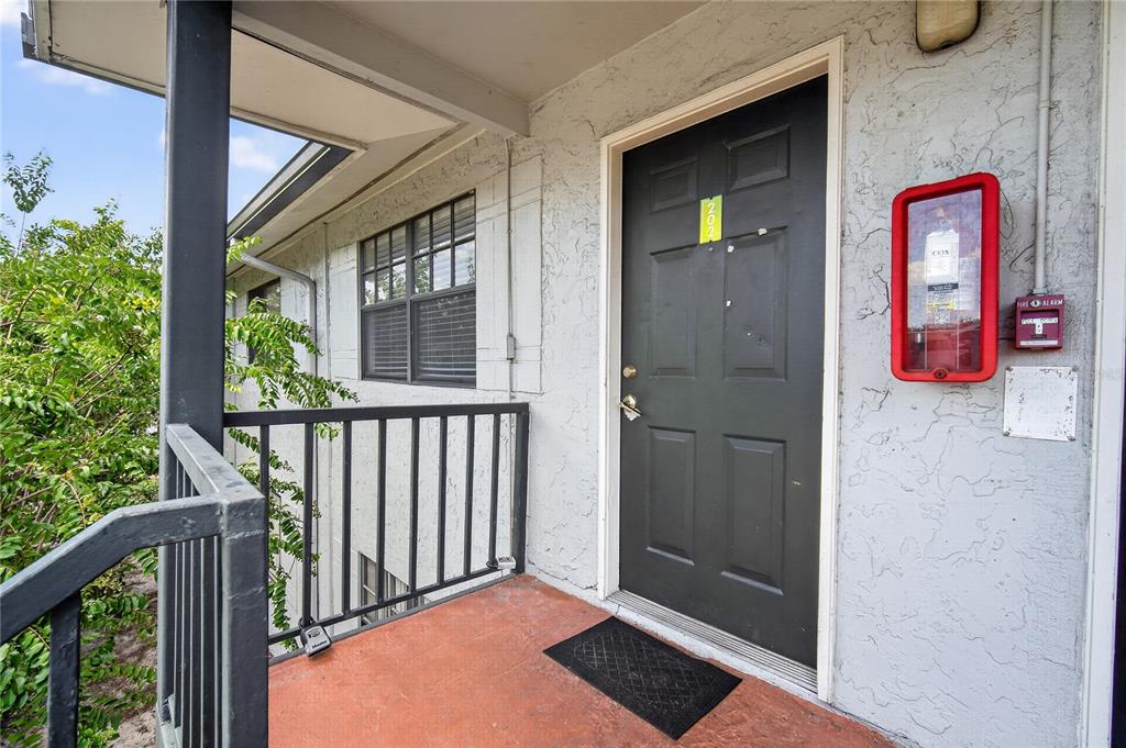 An exterior view of an apartment entrance with a dark door and a fire alarm — 12405 OAK CEDAR PLACE UNIT 202, TAMPA, FL