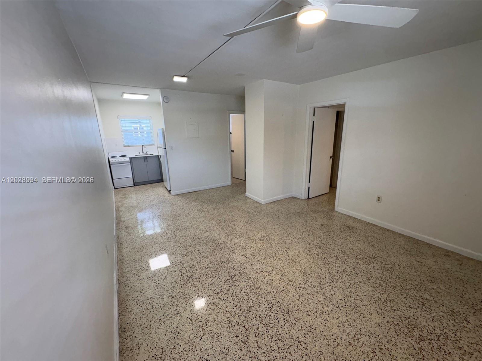 An open-concept living area features terrazzo flooring, a ceiling fan, and an adjacent kitchen — 320 W 10th St # 3, Hialeah FL 33010, HIALEAH, FL
