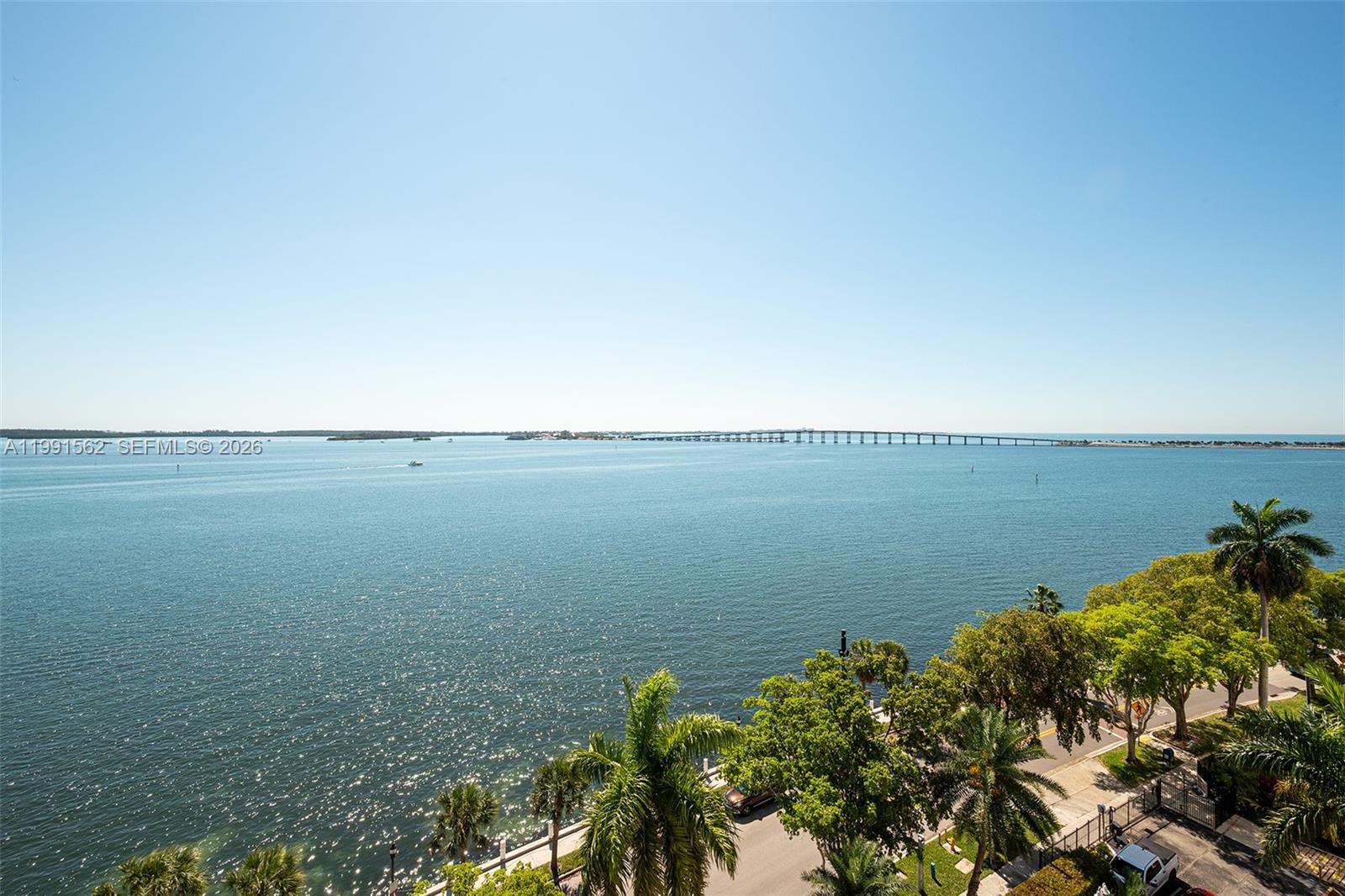 An elevated view shows a large body of water with a long bridge in the distance — 1420 Brickell Bay Dr # 1003A, Miami FL 33131, MIAMI, FL