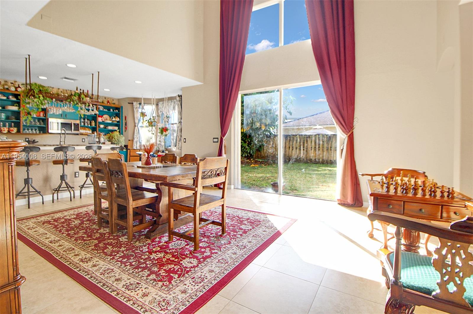 A dining room with a wooden table and chairs sits before a blue-cabinet kitchen — 1604 SE 16th St, Homestead FL 33035, HOMESTEAD, FL