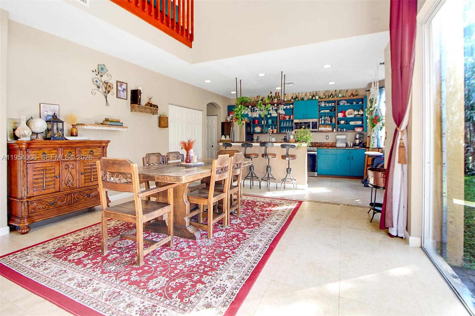 A kitchen features a breakfast bar with industrial stools and vibrant blue cabinetry — 1604 SE 16th St, Homestead FL 33035, HOMESTEAD, FL