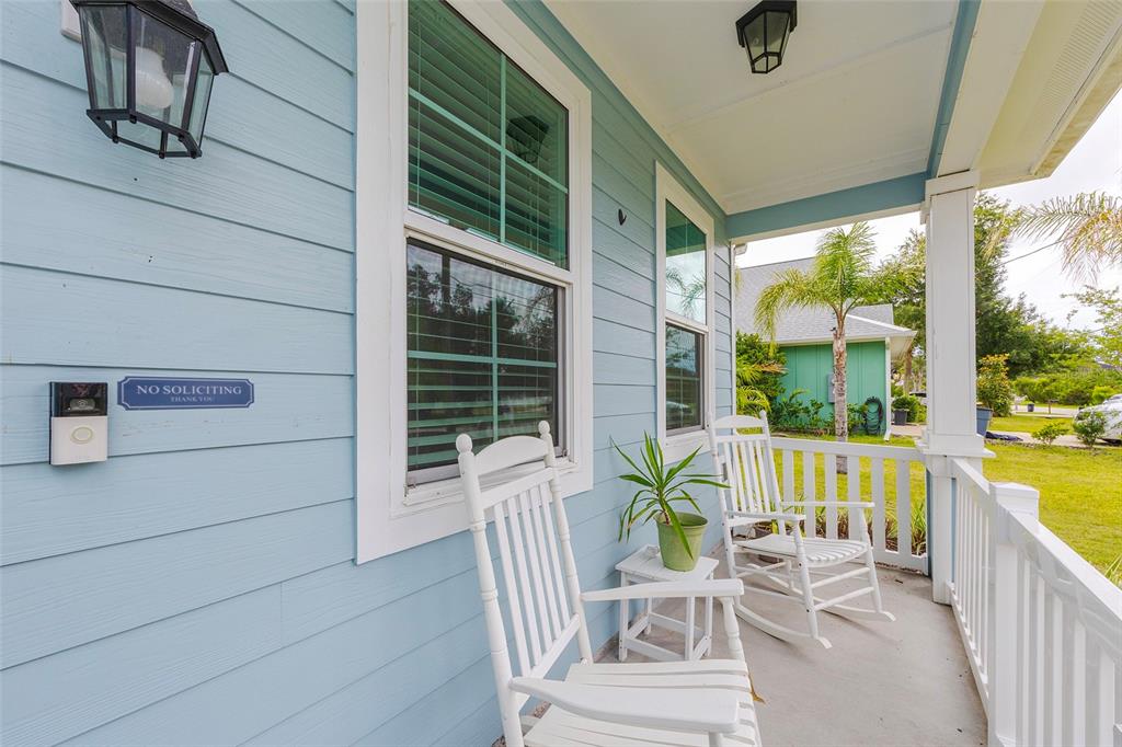 A light blue house exterior features a front porch with two white rocking chairs — 17 ROCKWELL LANE, PALM COAST, FL