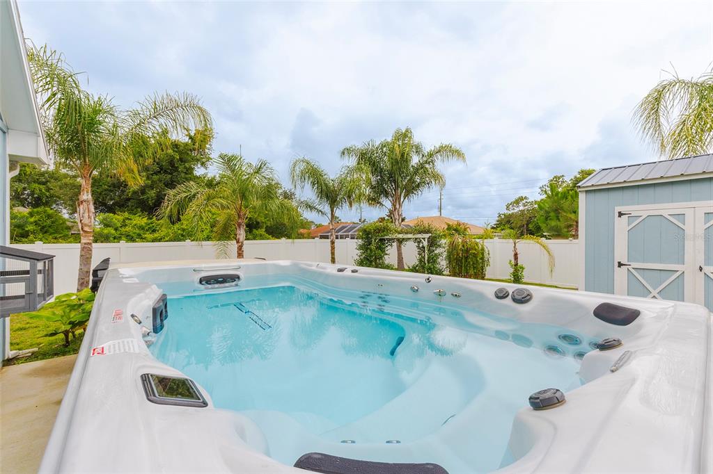 A large swim spa sits on a concrete patio in a fenced backyard with palm trees — 17 ROCKWELL LANE, PALM COAST, FL