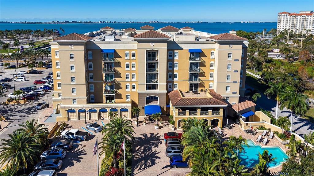 An aerial view of a multi-story tan apartment building with a pool and parking lot — 1064 N TAMIAMI TRAIL UNIT 1435, SARASOTA, FL