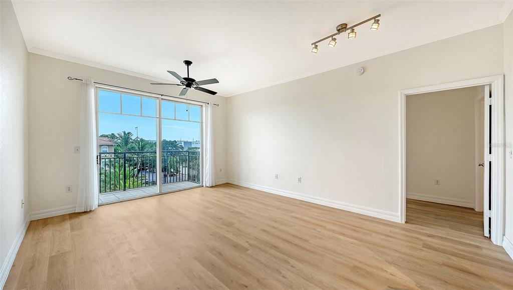 An empty room features light wood-look flooring, a ceiling fan, and a balcony with railings — 1064 N TAMIAMI TRAIL UNIT 1435, SARASOTA, FL