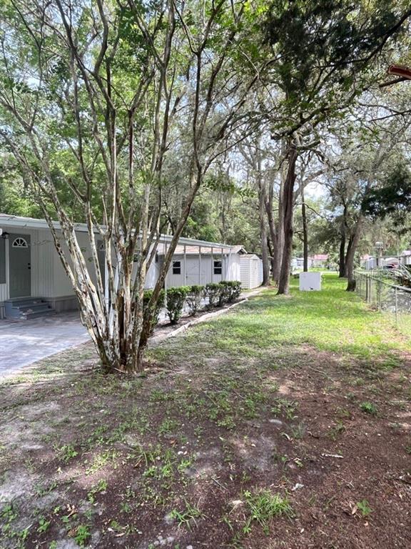 A side view of a mobile home with a large tree and a grassy yard — 11012 NW 113TH PLACE, CHIEFLAND, FL