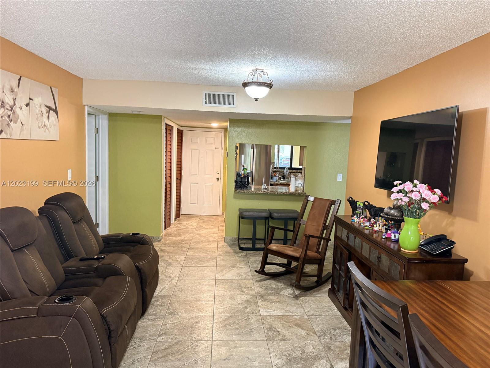 A living room features brown reclining chairs, a rocking chair, and a kitchen pass-through window — 191 Lakeview Dr # 103, Weston FL 33326, WESTON, FL
