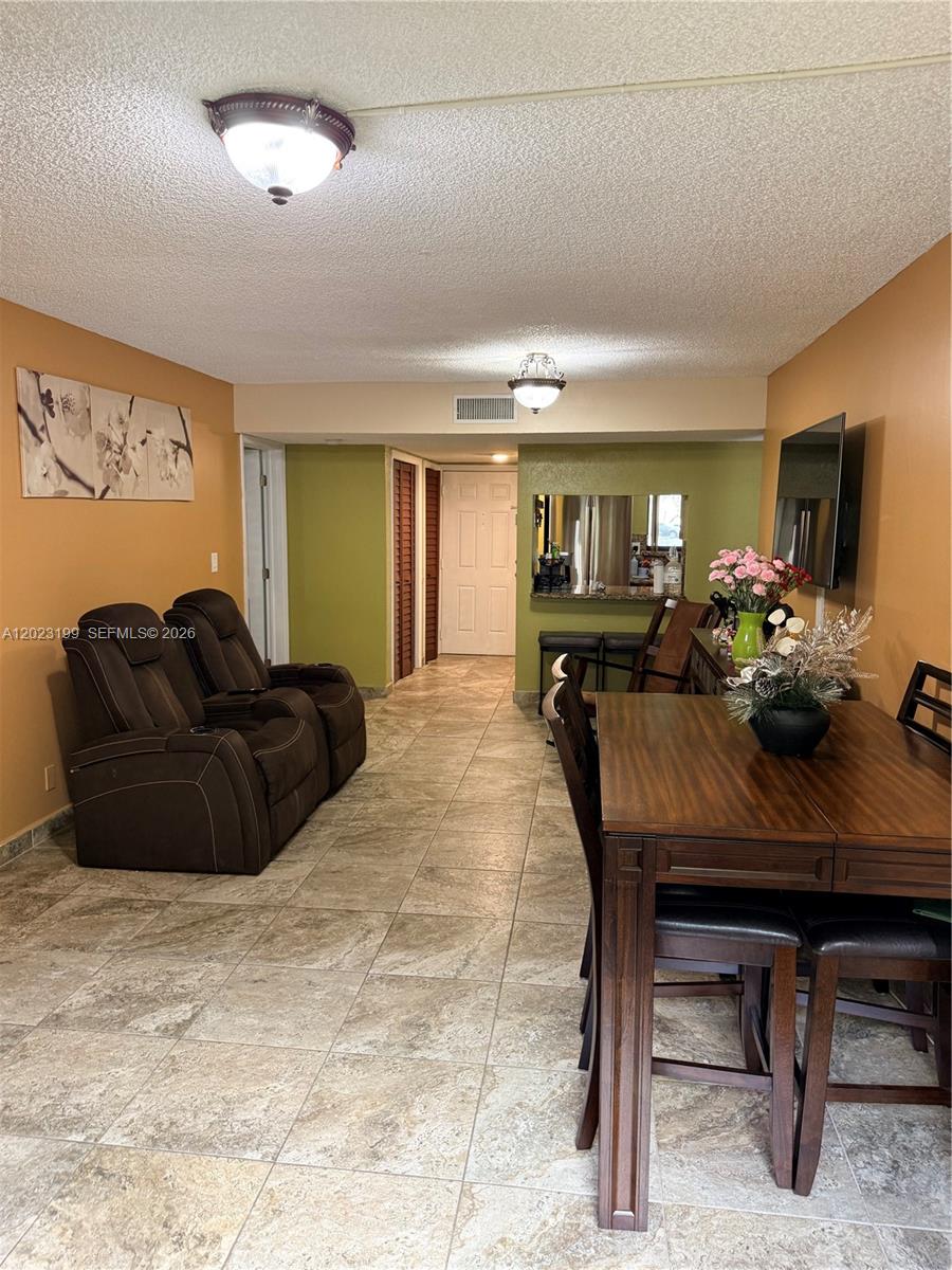This open-concept living and dining area features tile flooring, tan walls, and a pass-through window — 191 Lakeview Dr # 103, Weston FL 33326, WESTON, FL