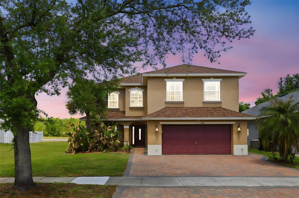 A two-story house with a tan exterior, a red garage door, and a paved driveway — 824 LAKE BISCAYNE WAY, ORLANDO, FL