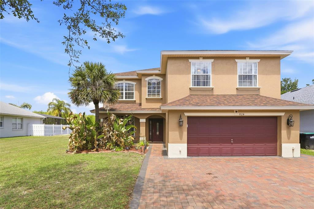A two-story tan stucco house with a brown shingle roof and a paved driveway — 824 LAKE BISCAYNE WAY, ORLANDO, FL