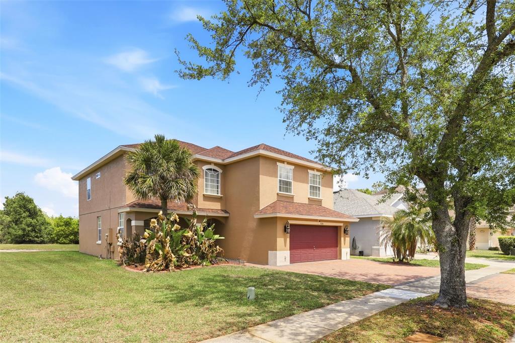 A two-story tan house with a red garage door and a large tree in front — 824 LAKE BISCAYNE WAY, ORLANDO, FL
