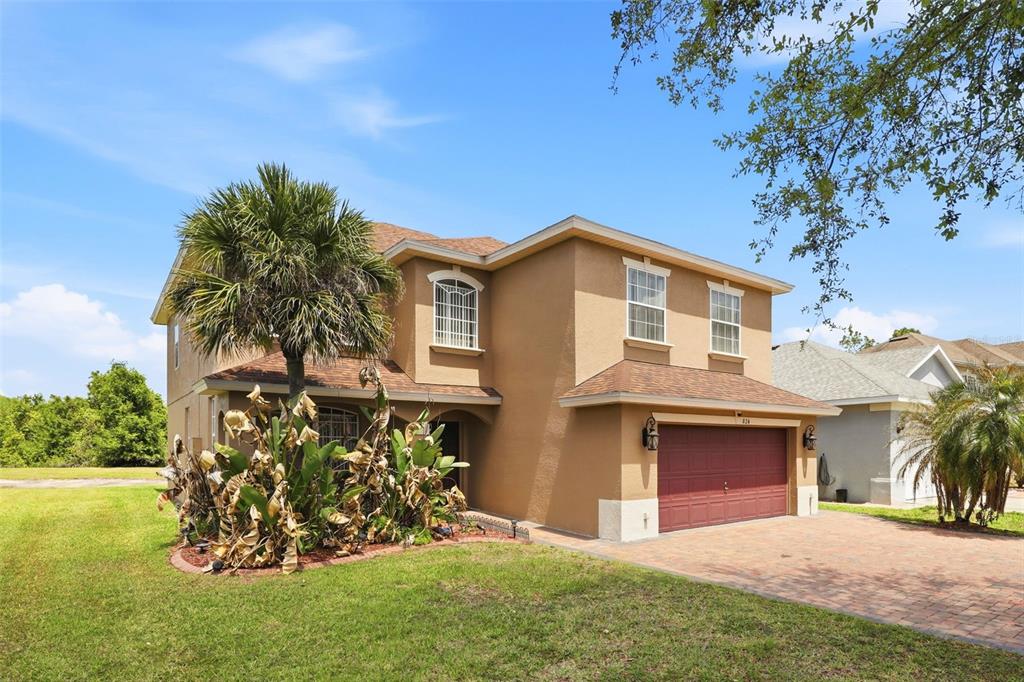 A two-story tan stucco house with a red garage door and a palm tree — 824 LAKE BISCAYNE WAY, ORLANDO, FL