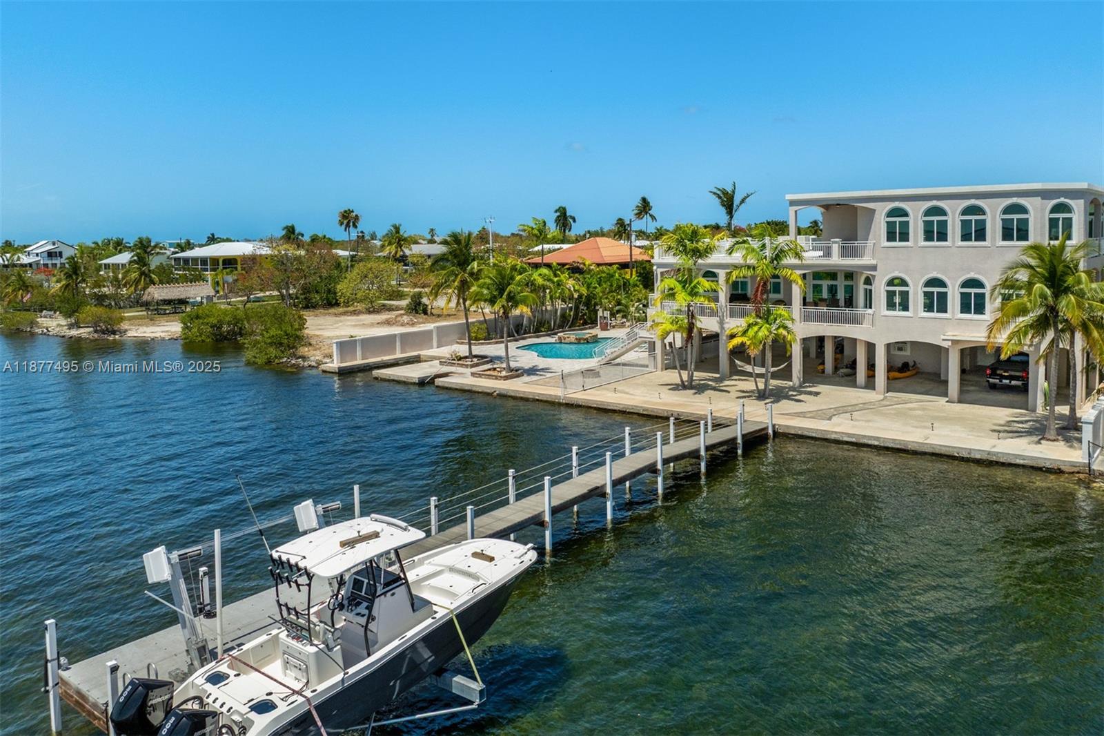 An aerial view shows a multi-story house with a pool, dock, and boat on water — 3742 Seagrape St, Big Pine FL 33043, BIG PINE, FL