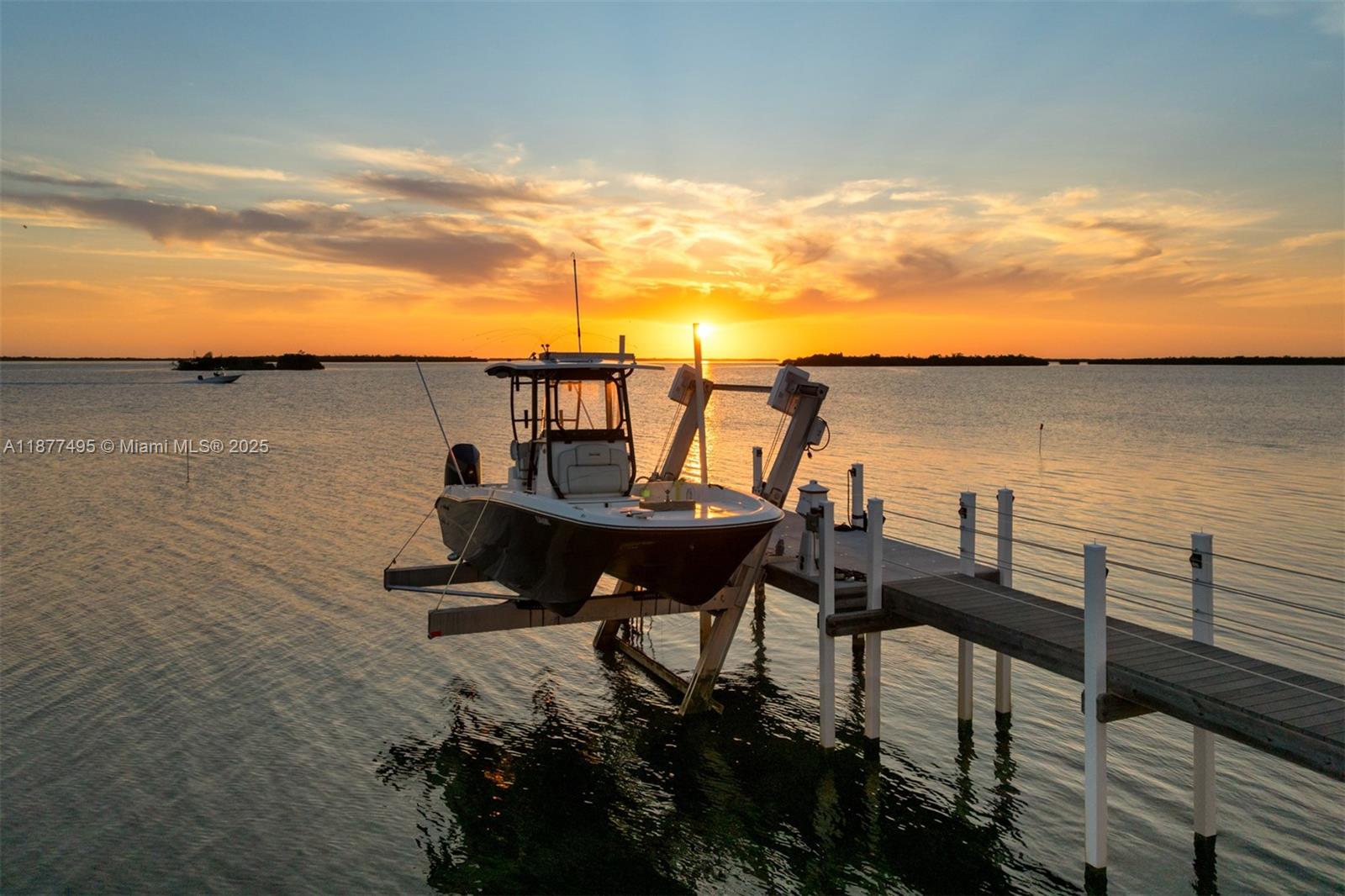 A boat sits on a lift at the end of a dock during sunset — 3742 Seagrape St, Big Pine FL 33043, BIG PINE, FL