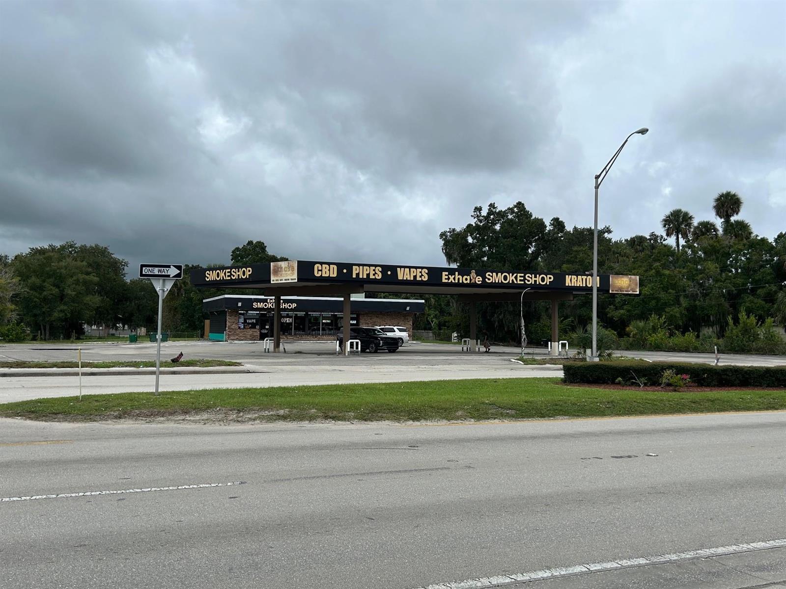 A smoke shop with a large canopy stands on a paved lot under a cloudy sky — 1705 S Parrott Avenue, Okeechobee FL 34974, OKEECHOBEE, FL