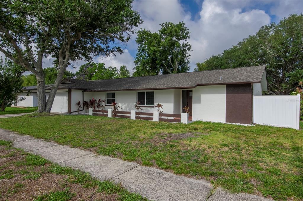 A single-story white house with brown trim and a low-profile fence sits on a lawn — 1689 MONTEREY DRIVE, CLEARWATER, FL