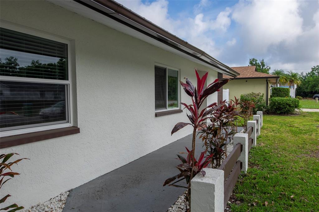 A walkway with a low wooden fence leads along the side of a white house — 1689 MONTEREY DRIVE, CLEARWATER, FL
