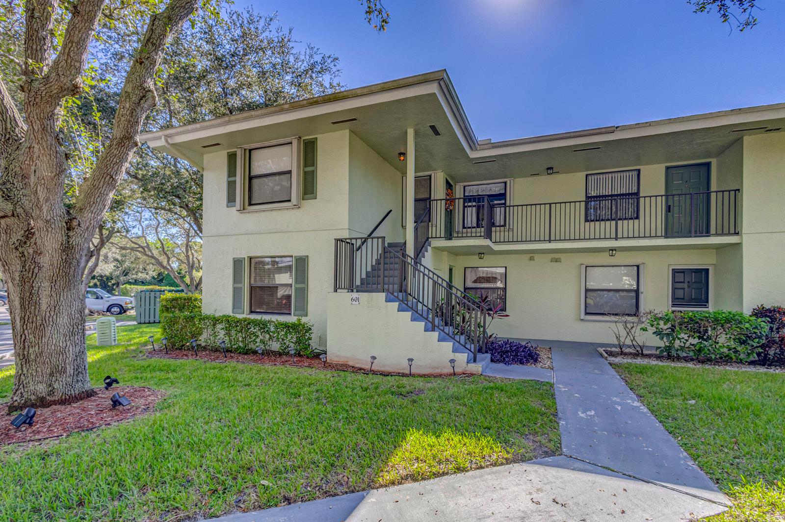A two-story apartment building with light green stucco walls, a staircase, and a walkway — 601 Sabal Ridge Circle # A, Palm Beach Gardens FL 33418, PALM BEACH GARDENS, FL