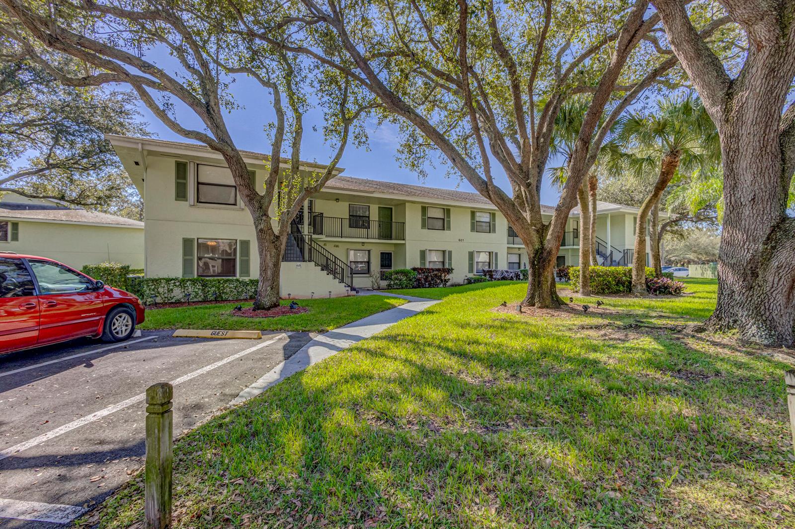 A two-story apartment building with light-colored stucco walls, green shutters, and a guest parking space — 601 Sabal Ridge Circle # A, Palm Beach Gardens FL 33418, PALM BEACH GARDENS, FL