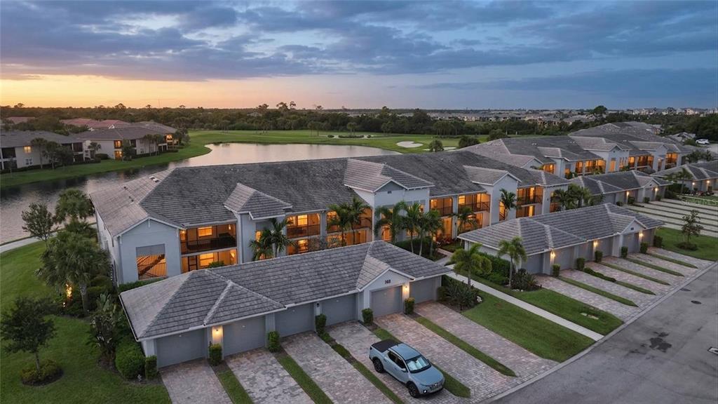 An aerial view of a multi-story residential building with attached garages and a nearby lake — 14040 HERITAGE LANDING BOULEVARD UNIT 125, PUNTA GORDA, FL