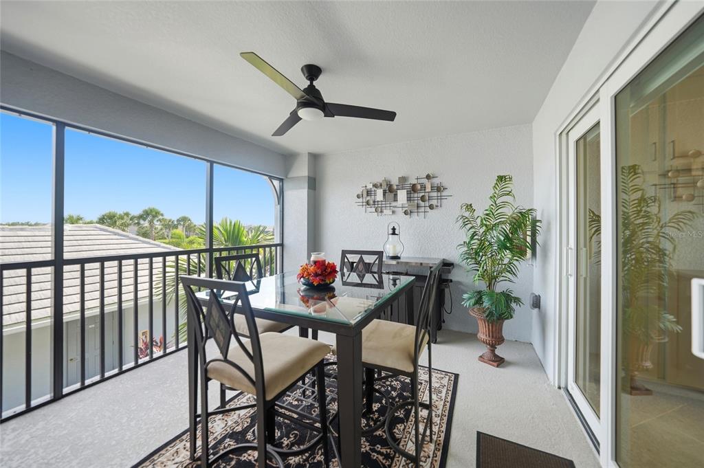 A screened-in balcony features a glass-top dining table, four chairs, a ceiling fan, and plants — 14040 HERITAGE LANDING BOULEVARD UNIT 125, PUNTA GORDA, FL