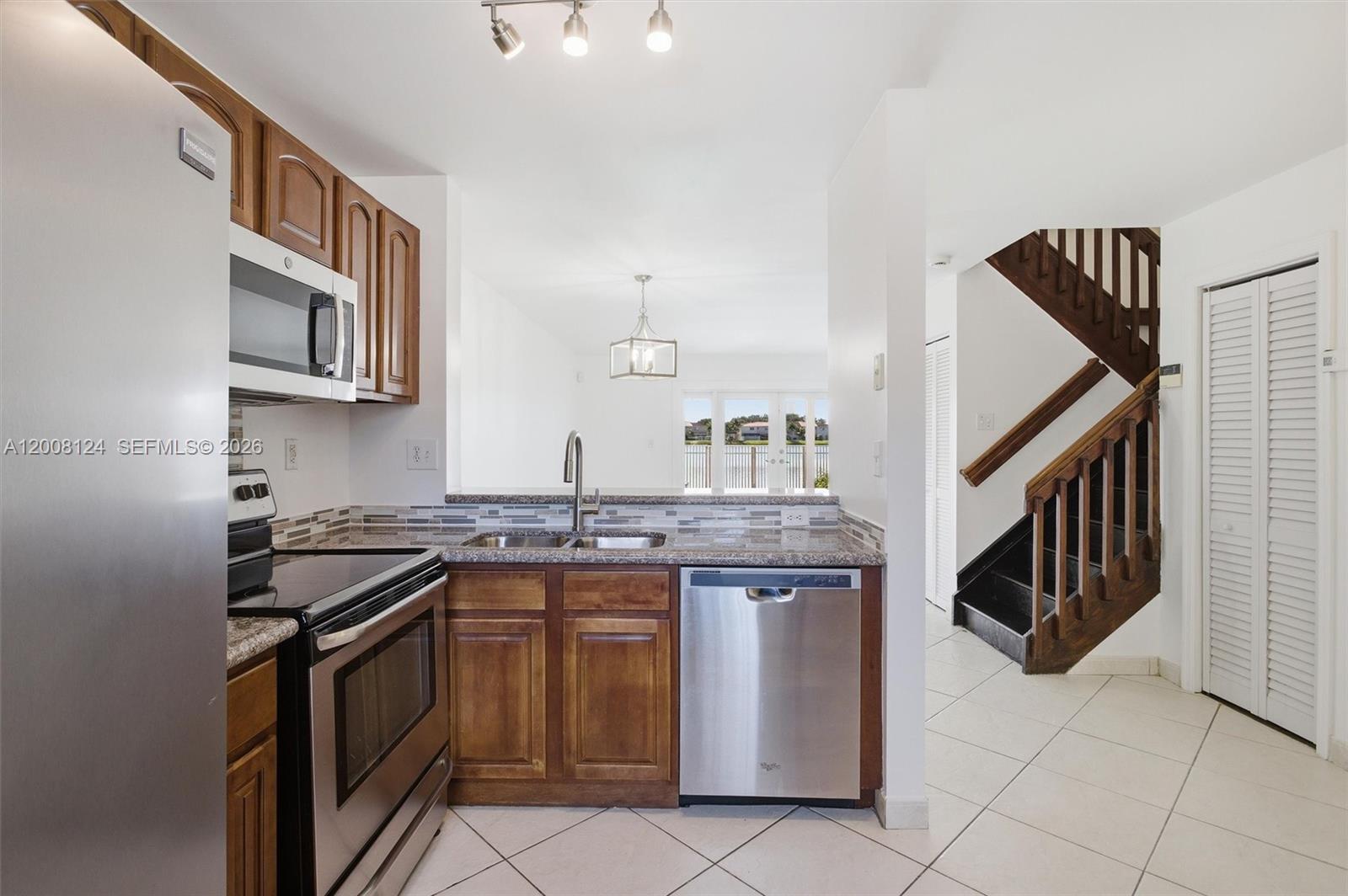 A kitchen with wood cabinets, stainless steel appliances, and a view of a waterfront patio — 17530 SW 139th Ct, Miami FL 33177, MIAMI, FL
