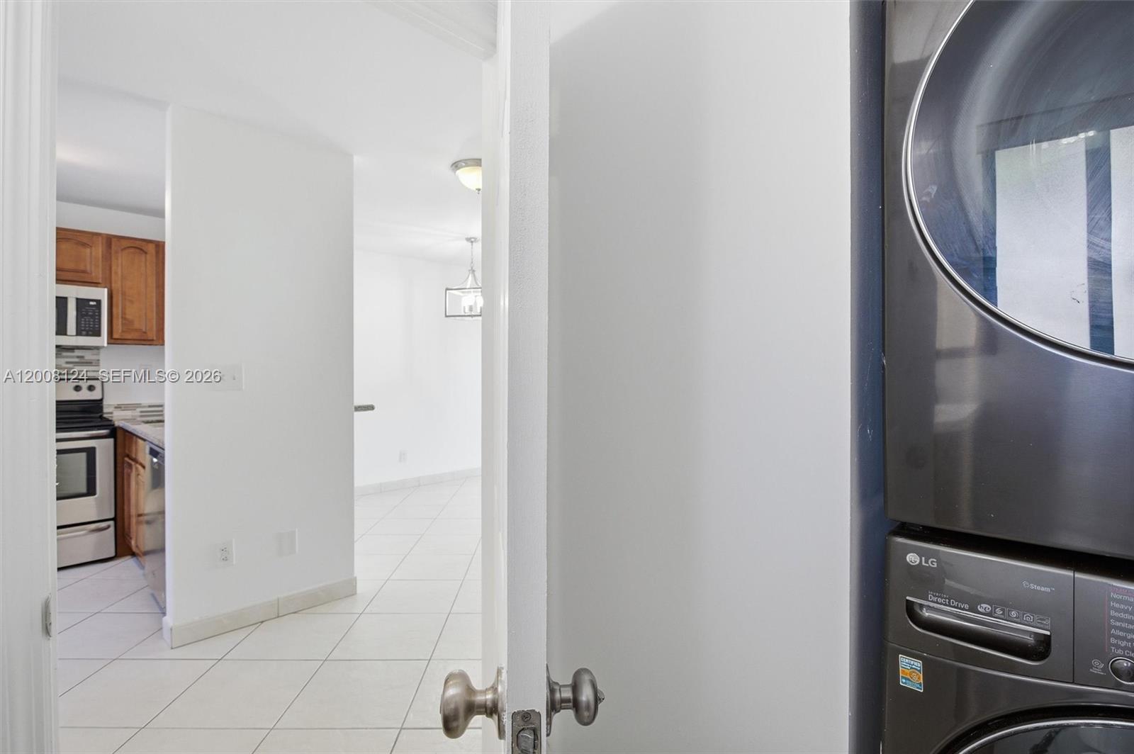 A laundry closet with a stacked washer and dryer opens into a tiled kitchen area — 17530 SW 139th Ct, Miami FL 33177, MIAMI, FL